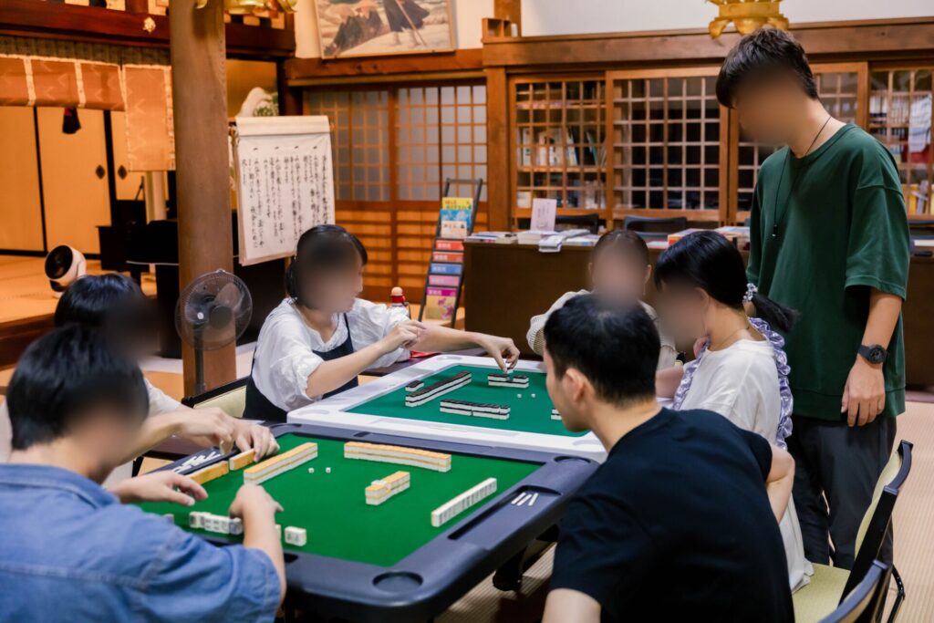 お寺の広間で麻雀卓をかこむ親たち